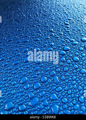 Condensation water droplets on a shiny blue metallic surface in a cold temperature background Stock Photo
