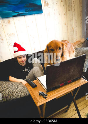 A boy and his dog attend a virtual class in December 2020. Stock Photo