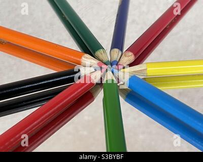 Colorful pencils arranged in a pinwheel on mirrored surface with reflections Stock Photo