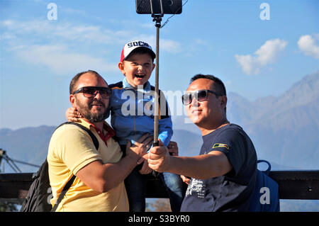 Two men with a child have fun taking a selfie in the mountains Stock Photo