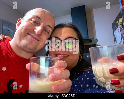 A mixed race couple take a selfie at Christmas with celebratory drinks in hand. Stock Photo