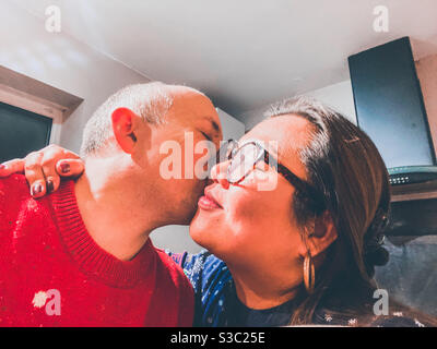 A mixed race couple share a kiss on the cheek. Stock Photo