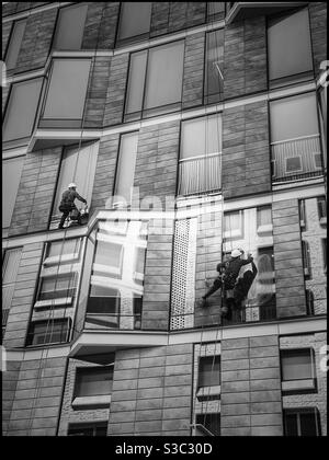 Black and white photo of window cleaners busy working on a building in Silo district of the V&A Waterfront, Cape Town, South Africa. Stock Photo