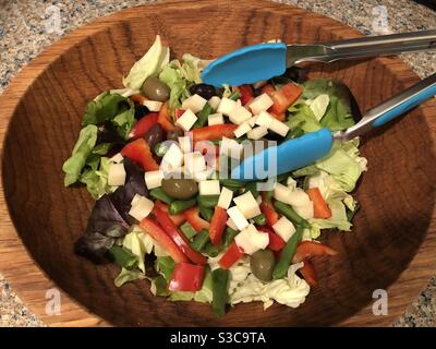 Mixed salad with cheese, Greek olives, red peppers, green beans and lettuce greens in a wooden bowl. Stock Photo