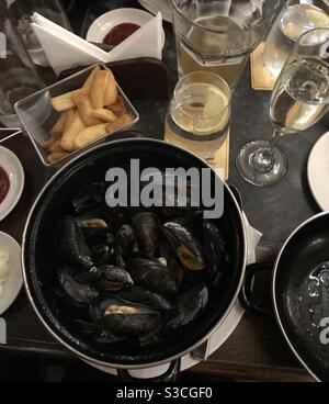 A pot of moules marinières mussels cooked in white wine served with French fries Stock Photo