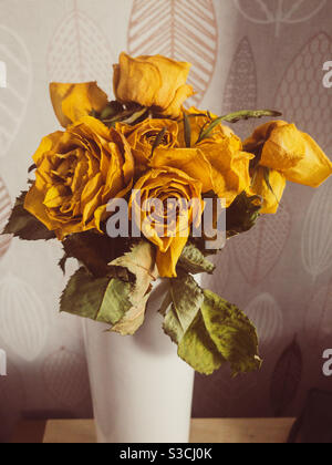A vase of yellow roses that have aged, dried up and withered. Stock Photo