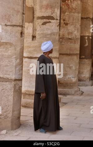 Egyptian man in thobe and headdress walks through Luxor temple patrolling the tourists in Egypt Stock Photo Alamy