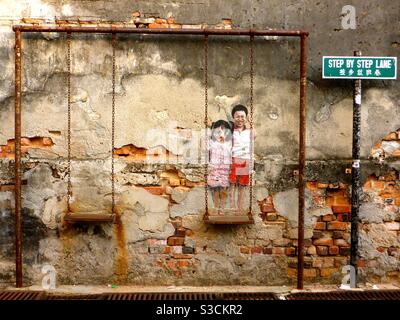 Brother and sister on a swing street art by Louis Gan Georgetown Penang Malaysia Stock Photo