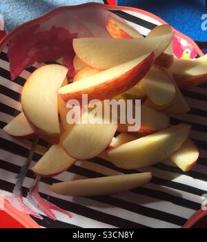 Close up of a sliced apple on a decorative striped plate Stock Photo