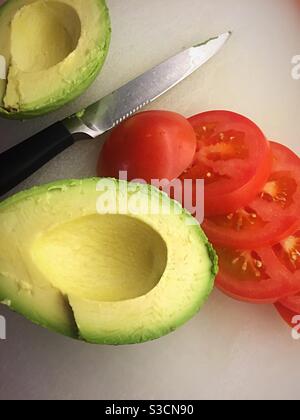 Close up of fresh avocados and sliced tomatoes on a cutting board and residential kitchen, USA Stock Photo