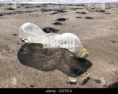 Empty plastic bottle left on the beach causing pollution Stock Photo