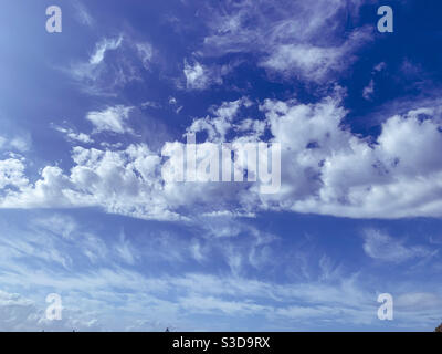Majestic lines of light fluffy white cumulus clouds of different shapes and thickness with a bright blue sky behind Stock Photo