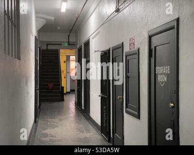 LOS ANGELES, CA, NOV 2020: white interior corridor with black doors inside building in Downtown warehouse district, yellow wall at far end and sunset coming through window Stock Photo