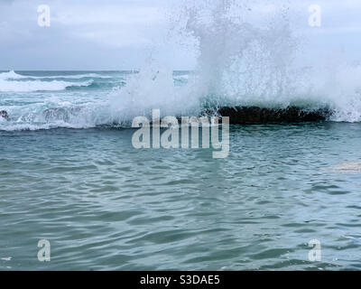 Surf crashing over the edge of the Rock pool Stock Photo