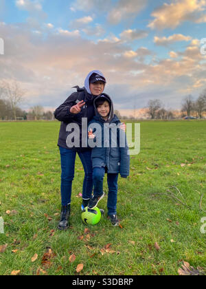Two young brothers posed together for a portrait in a park. Stock Photo