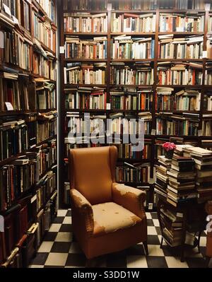 Old leather armchair in a room full of books Stock Photo