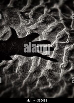 Dramatic shadow of a hand on a textured sandy surface Stock Photo