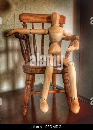 Small wooden figure man woman sitting in miniature antique wooden chair Stock Photo