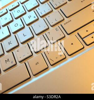 View of the keyboard of a laptop highlited by blue amd yellow lights Stock Photo