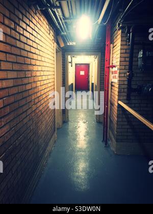 Long basement hallway with a red door at the end in an apartment building in New York City, USA Stock Photo