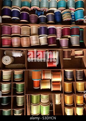 Multi coloured cotton thread reel spools in a sewing box draw for clothing repairs Stock Photo