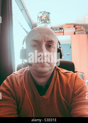 Middle aged man who rking from home from a desk in a child’s bedroom. Stock Photo