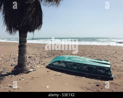 Green fishing boat left left on beach Stock Photo