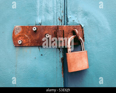 Door closed with a padlock on an led, rusty latch. Stock Photo
