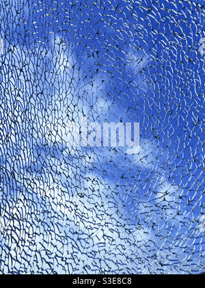 Intricate pattern formed by toughened glass which has shattered against a background of sky