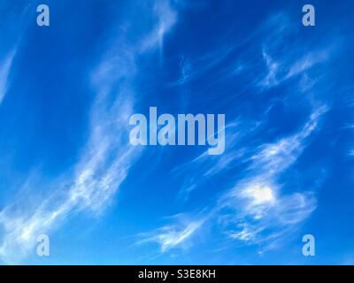 Deep blue sky with wisps of white cloud. Background. Stock Photo