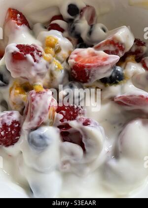 Raspberries, blueberries, strawberries and passionfruit with plain yoghurt in a china bowl Stock Photo