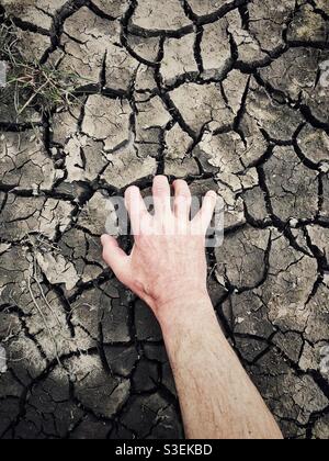 Human hand digging clawing and scratching at a cracked and dried up earth in a drought concept Stock Photo