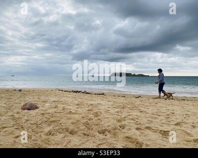 Lady walking her dog on the beach in winter Stock Photo