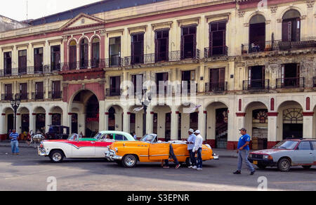 Local men with large colourful vintage American cars in Havana, Cuba Stock Photo