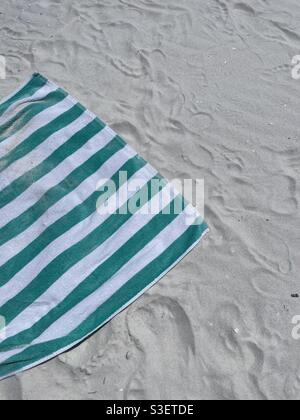 Green and white beach towel on white sand beach Stock Photo
