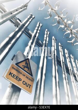 A warning sign saying keep out of a fenced and Barb wired no-go area to keep tresspassers out Stock Photo