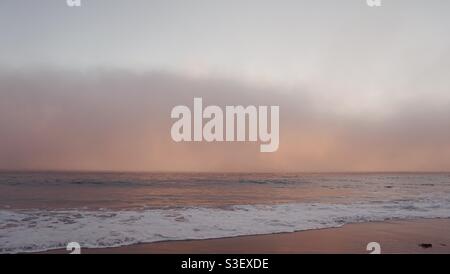 Marine layer swiftly moving onto beach during sunset. Stock Photo