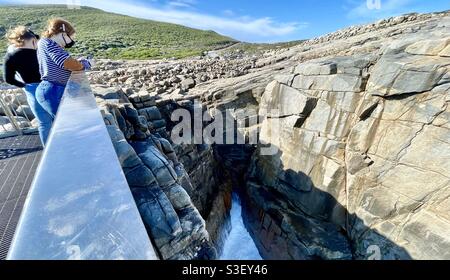 Two women on cantilevered viewing platform at the Gap cliff of granite rock in Torndirrup National Park along Southern Ocean coastline, Great Southern region near Albany Western Australia Stock Photo