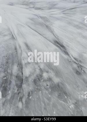 Grunge abstract background of black sediment on white beach sand Stock Photo