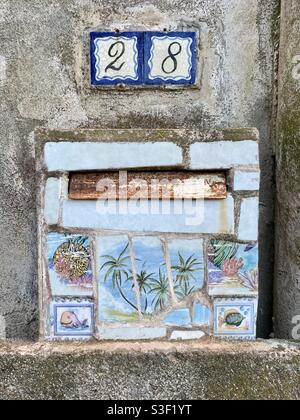Beautiful rusty painted landscape with palm trees on a mailbox with number 28, south of France Stock Photo