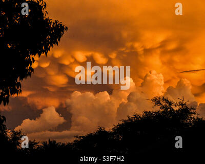 Building monsoon clouds during an intense orange sunset. Stock Photo