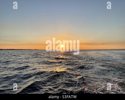 Golden sunset skies with boat wake waves over the Gulf of Mexico water Florida Stock Photo