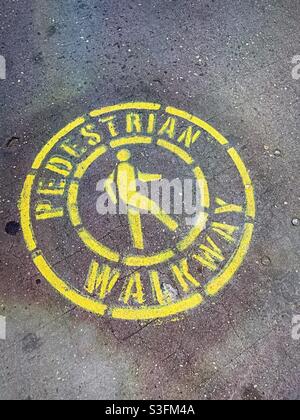 A painted pedestrian walkway stencil with pictogram on a New York City sidewalk, USA Stock Photo