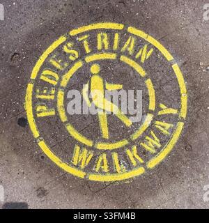 Pedestrian walkway stencil in yellow paint on a Manhattan sidewalk, NYC, USA Stock Photo