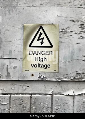 Old weathered danger high voltage sign on cracked and peeling wooden background Stock Photo