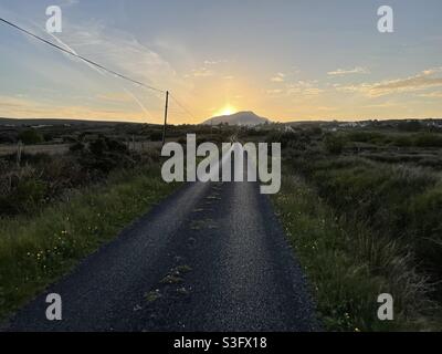 An empty road leading up to a sunset on Achill Island, County Mayo, Ireland.