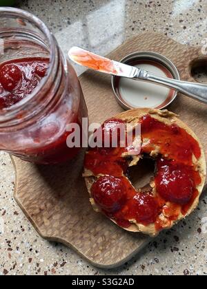 Homemade strawberry jam with natural peanut butter on a toasted bagel. Stock Photo