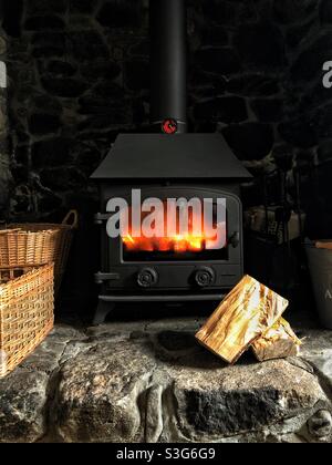 Cozy stone cottage home interior with a fire blazing in a wood burning stove fireplace Stock Photo