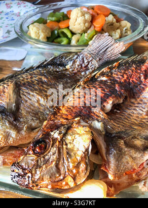 Baked tilapia fish served with stir fried vegetables. Stock Photo