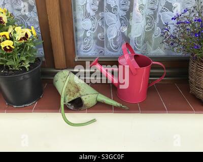 Old and New Watering Cans on a Window Sill Stock Photo